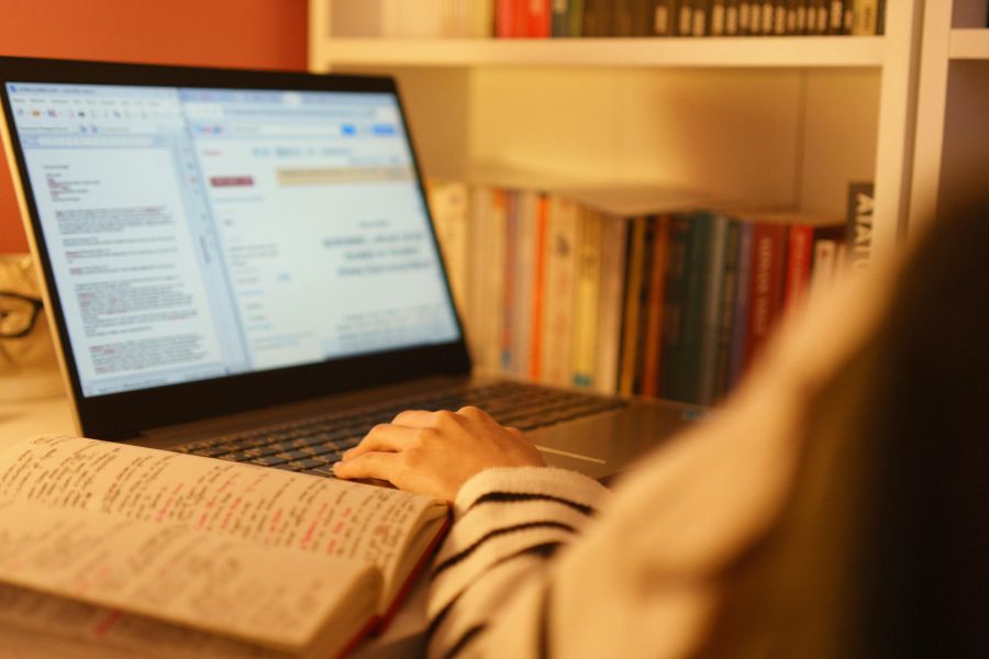Une personne travaille sur un ordinateur portable et consulte un carnet, se renseignant sur la propriété intellectuelle.